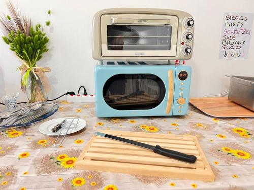 a toaster oven sitting next to a cutting board and a knife at Ostello Brebei Niedda - Base Camp Outdoor & View in Gonnesa
