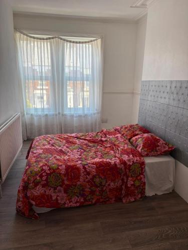 a bedroom with a bed with a red comforter and a window at Goody Suites in Newcastle upon Tyne
