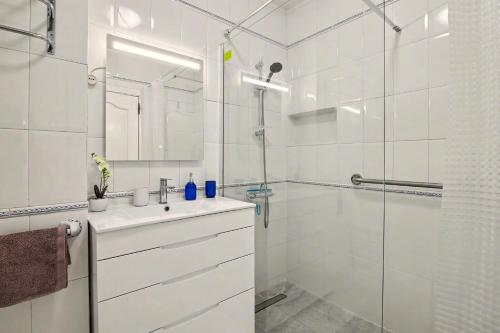 a white bathroom with a sink and a shower at T2 Tivoli in Vilamoura