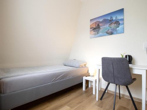 a small bedroom with a bed and a chair at Die kleine Pension in Delmenhorst