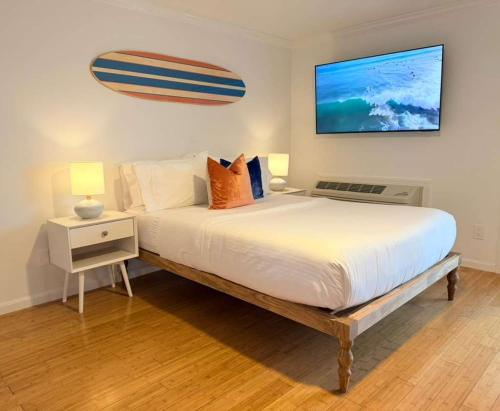 a bedroom with a large bed and a tv on the wall at Surfside - Boutique Studio Condo with Pool in Hampton