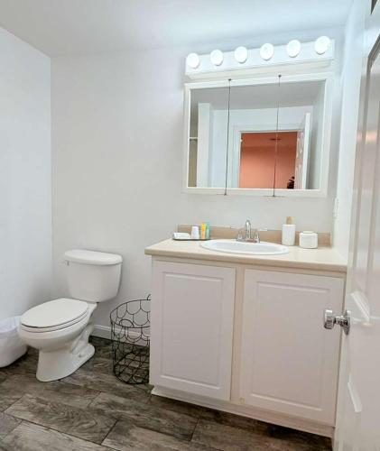 a bathroom with a toilet and a sink and a mirror at Surfside - Boutique Studio Condo with Pool in Hampton