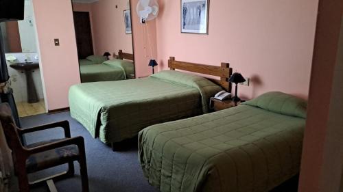 a hotel room with two beds and a chair at Hotel Alicante in Chillán