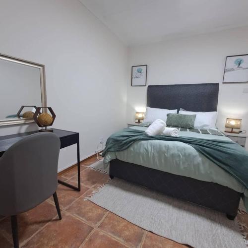 a bedroom with a bed and a desk with a mirror at Villa Central in Francistown