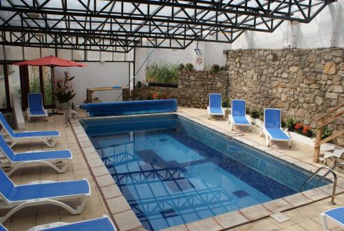 a swimming pool with blue chairs and a table at Hotel La Belle Aude in Matemale