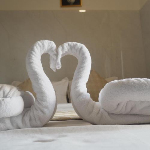two towels shaped like swans sitting on a bed at Amani Beach Stay in Māvalli