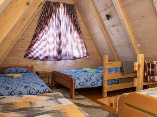 a attic room with two beds and a window at WildBeauty Grebaje in Vusanje