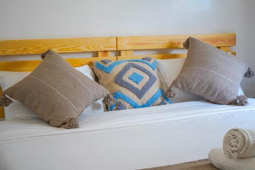 a white bed with pillows and a wooden headboard at Ocean Breeze Guest House in Tamraght Ouzdar