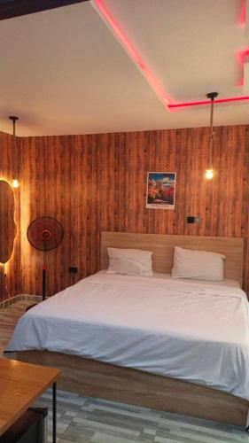 a bedroom with a white bed with wooden walls at The Royam Hotel and Apartments in Ibadan