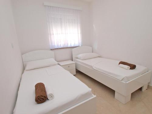 a white room with two beds and a window at Apartments Medulin 396 in Medulin
