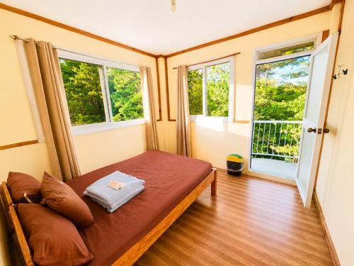 a small room with a bed and two windows at 3 Mins Drive to Marlboro Hills - Sagada Dad's Homestay in Sagada