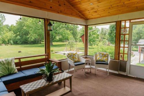 a screened in porch with a blue couch and chairs at Family Friendly Getaway with Fire Pit & Swing Set in Geneva