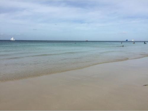 a beach with people in the water and a sail boat at Nigi Nigi Nu Noos 'e' Nu Nu Noos in Boracay