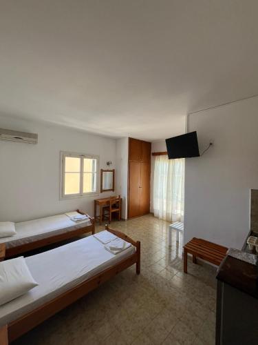 a large room with two beds and a television at Avgoustina Venus Studios in Benitses