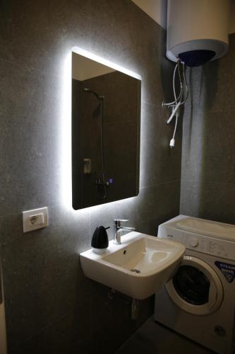 a bathroom with a sink and a washing machine at Kron Apart Hotel Golem in Golem