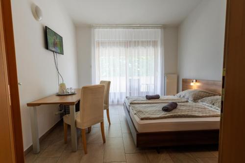 a bedroom with a bed and a table and a desk at Jacht Apartmanok in Balatonfüred