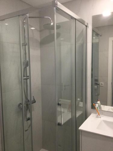 a glass shower in a bathroom with a sink at HabiKuchta Foz in Figueira da Foz