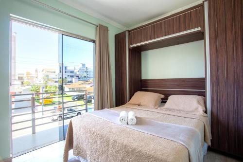 a bedroom with a large bed with two towels on it at POUSADA JURERE in Florianópolis
