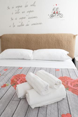a bed with white sheets and towels on it at Enza House in Chioggia