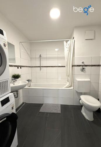a bathroom with a toilet and a tub and a sink at BEGE APARTMENTS WorkSpace in Marl