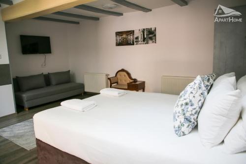 a bedroom with a large white bed and a couch at ApartHome in Makó