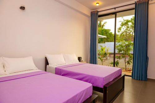 two beds in a room with purple sheets at Port Royal Residence in Trincomalee