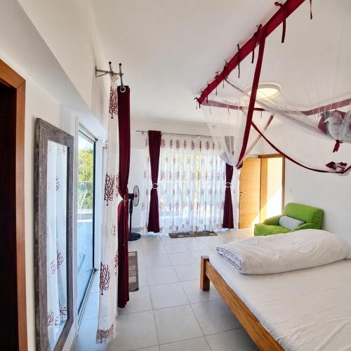 a bedroom with a bed and a large window at Villa Céllia in Tsivonoakely