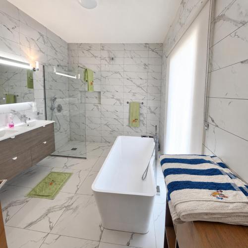 a white bathroom with a tub and a sink at Villa Céllia in Tsivonoakely