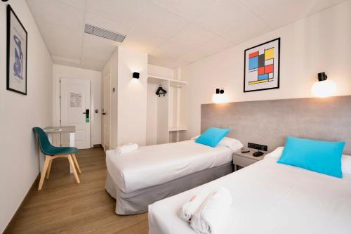 a hotel room with two beds and a chair at Hotel Universal Murcia in Murcia