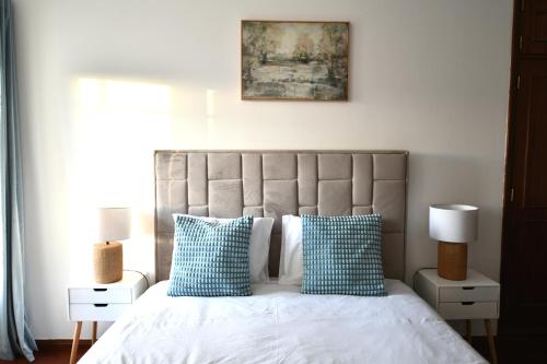 a bedroom with a bed with blue and white pillows at Casa do Sol Wellness Home in Óbidos