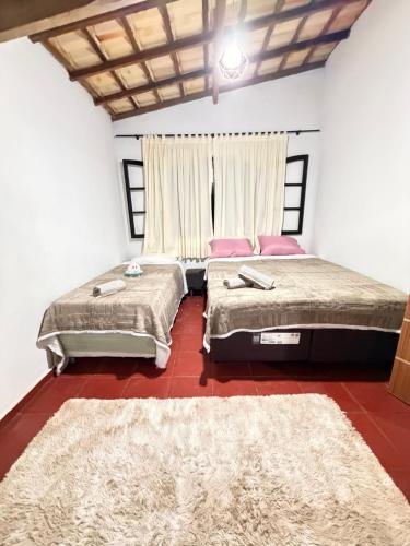 two beds sitting in a room with a red floor at Sítio Sombra da Figueira in Paty do Alferes