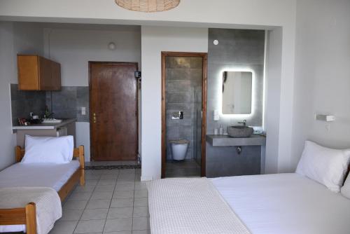 a bedroom with two beds and a bathroom with a sink at Venus Studios in Vlachata