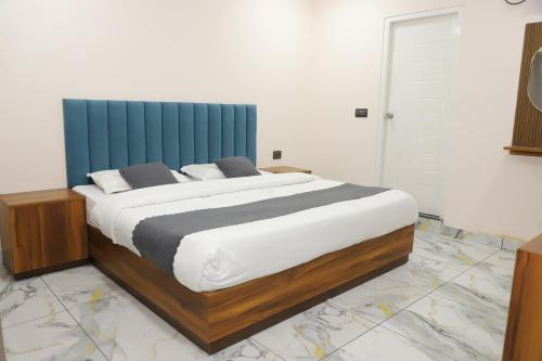 a bedroom with a large bed with a blue headboard at Hotel Velvet Vista in Rishīkesh