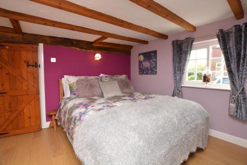 a bedroom with a bed with purple walls and a window at 1 Bed in Gainsborough oc-66230 in Heapham