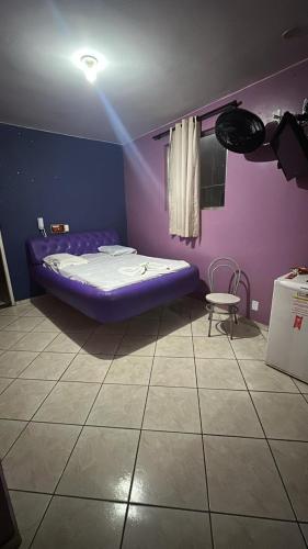 a purple bedroom with a bed and a chair at Londres hotel thur in Brasília