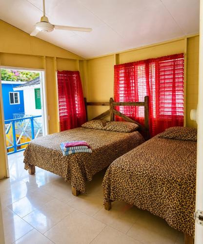 two beds in a room with red curtains at Rooms on the 7 Mile in Negril