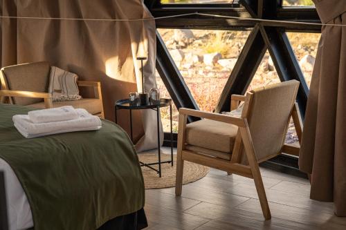 a room with two chairs and a bed and a window at Glamping Astrapia - Cafayate in Cafayate