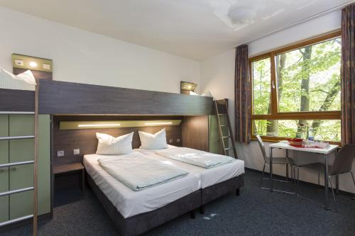 アーヘンにあるユーゲントヘアベルゲ アーヘンのベッドルーム1室(ベッド1台、テーブル、窓付)