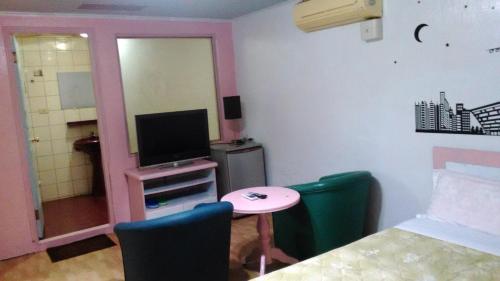 a room with a bed and a table and a tv at San Ho Hotel in Taoyuan