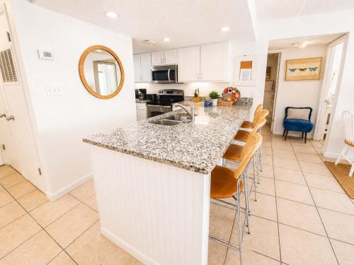 a kitchen with a counter and a kitchen island with chairs at Sugar Beach153- 4 pools beachfront in Gulf Shores