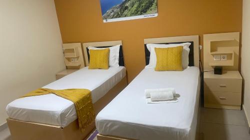 two beds in a small room with yellow pillows at Residencial FSFA in Praia