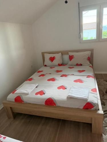 a bed with red flowers on it in a bedroom at Airport Studio apartman ravna gora in Mitrovići