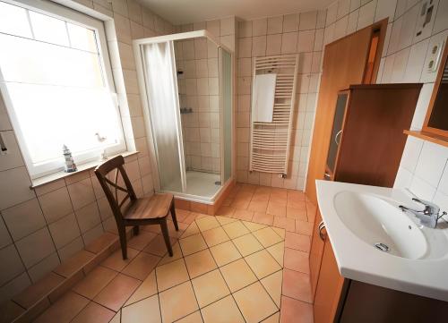 a bathroom with a sink and a chair and a shower at Haus 12 in Röbel