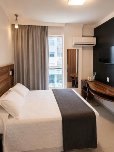 a bedroom with a bed and a desk and a window at Atlântico Golden Apart Hotel in Santos