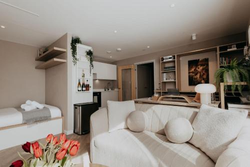a living room with a white couch and a kitchen at Saturn Studio by Navie Stays in Poole