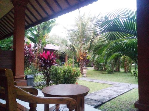 a patio with a table and chairs and palm trees at Suka Sari Cottages in Pemuteran