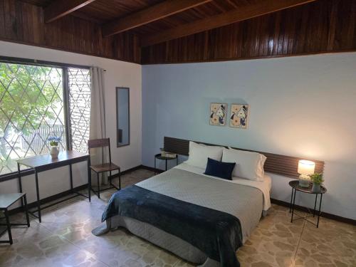 a bedroom with a bed and a desk and a window at Carolina Hostel in San José