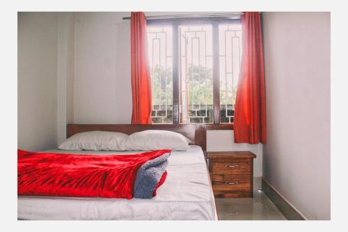 a bedroom with a bed with red curtains and a window at Mini Emphum 2BHK Apartment in Namsai