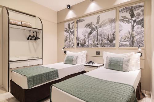 a hotel room with two beds and a painting on the wall at Havana Palace Hotel II Uberaba in Uberaba