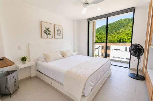a bedroom with a white bed and a large window at Miramonte Payande in Nimaima